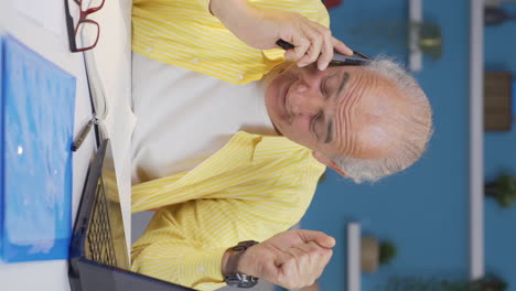 Vertical-video-of-Home-office-worker-old-man-getting-good-news-on-the-phone.